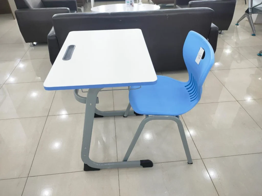 طاولة دراسة حديثة بسطح أبيض ومقعد بلاستيكي أزرق مصمم لطلاب المدارس، موضوعة في قاعة عرض أو فصل دراسي حديث